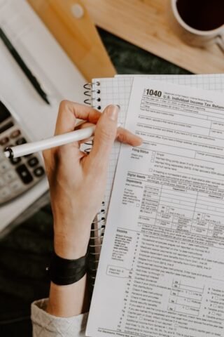 Person reviewing paperwork with calculator and laptop